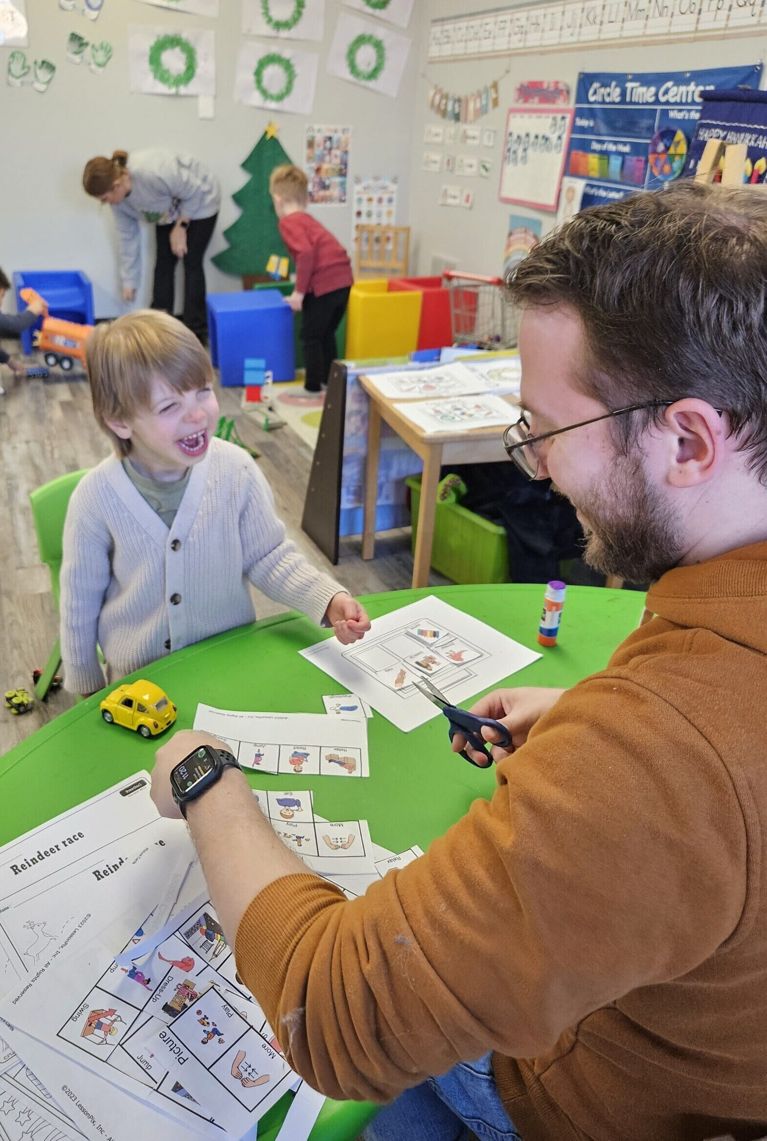 A child smiles happily at a therapist in a preschool setting, engaged in a speech-related activity within Step Forward Therapy's developmental preschool program.