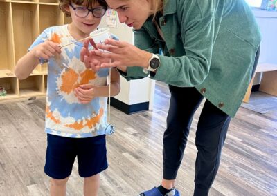 This photo is of one of our occupational therapists. She is closely looking at a craft that her and the child created. They both look on and are impressed.